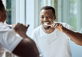 Man smiling while brushing his teeth