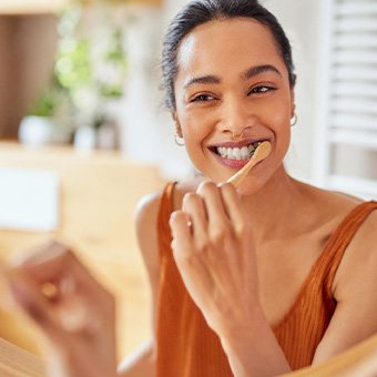 Woman smiling while brushing her teeth