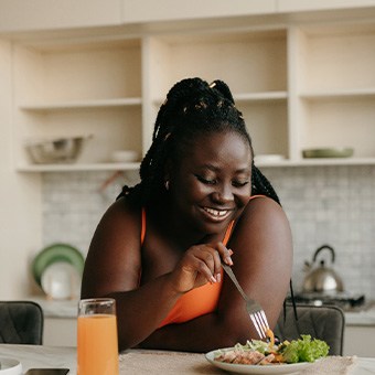 Woman smiling while eating healthy at home