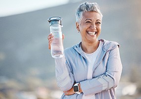 Woman smiling with water bottle on hike outside