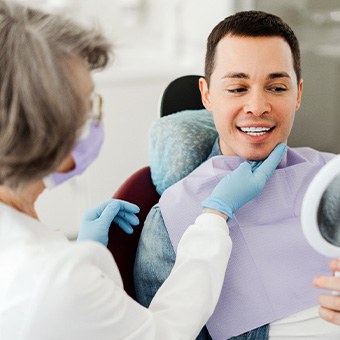 Man smiling at reflection in mirror with dentist