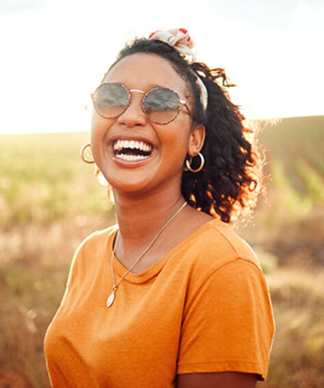 woman in orange shirt smiling in middle of field