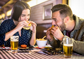 Man and woman eating burgers at restaurant