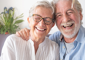 Senior woman being hugged from side by senior man