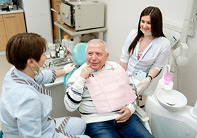 Senior dental patient pointing to mouth while talking to dentists