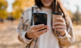 Looking at cell phone and holding coffee