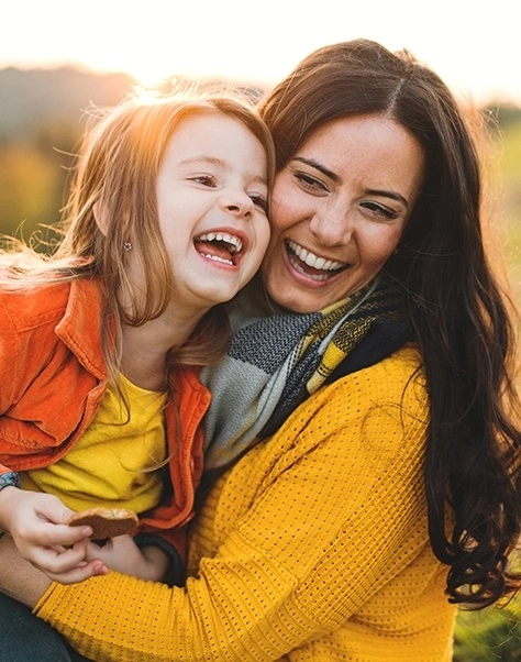 Mother hugging her young daughter outdoors