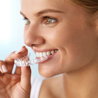 Woman placing Invisalign tray in her mouth