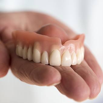 Hand holding a full denture