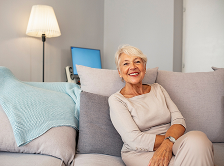Senior woman sitting on couch smiling