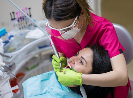 Female dental team member applying fluoride to patient's smile