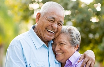 Smiling older man and woman hugging outdoors